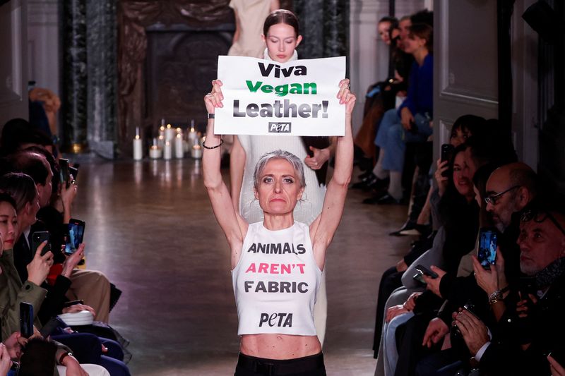 &copy; Reuters. ناشطة من منظمة أناس من أجل معاملة أخلاقية للحيوانات (بيتا) تحمل لافتة مكتوب عليها "فيفا فيجن ليذر" بعد اقتحام ناشطات عرض أزياء للمصممة فيكتور