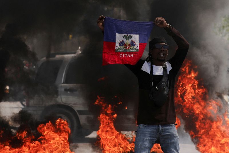 &copy; Reuters. متظاهر بيده علم هايتي خلال احتجاج على حكومة رئيس الوزراء أرييل هنري في بورت او برنس يوم الجمعة. تصوير: رالف تيدي إيرول - رويترز