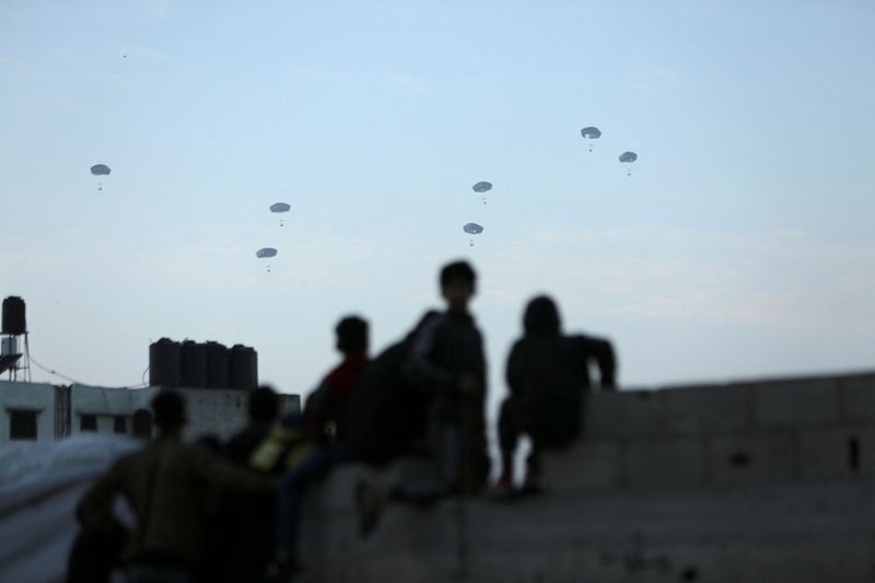 © Reuters. People watch as the US military carries out its first aid drop over Gaza, March 2, 2024. REUTERS/Kosay Al Nemer