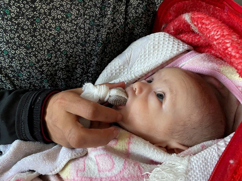 &copy; Reuters. FOTO DE ARCHIVO-La mujer palestina Warda Mattar alimenta a su recién nacido con dátiles, en lugar de leche, en medio de la escasez de alimentos y la falta de leche, en una escuela donde se refugian en Nuseirat en el centro de la Franja de Gaza. 25 de fe
