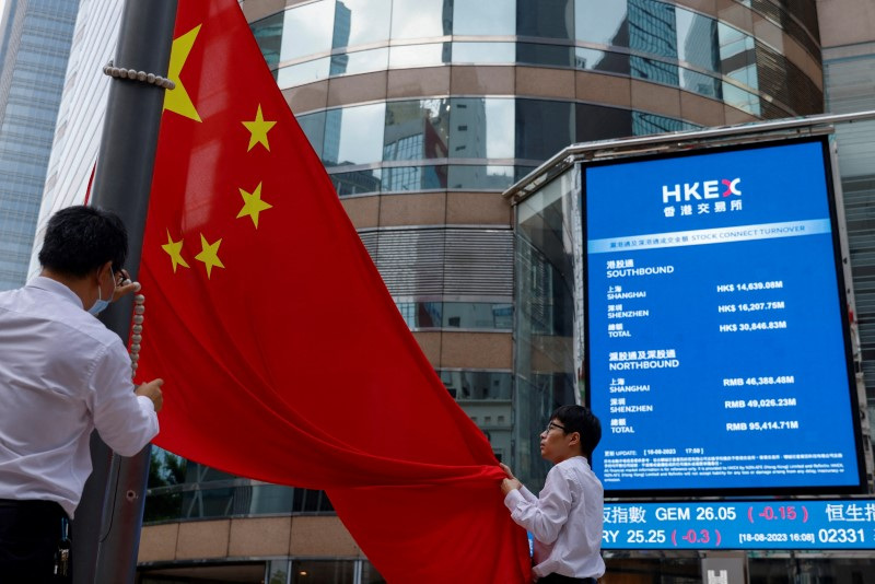 &copy; Reuters. FILE PHOTO: Staff lower Chinese national flag in front of screens showing the index and stock prices outside Exchange Square, in Hong Kong, China, August 18, 2023. REUTERS/Tyrone Siu/File Photo