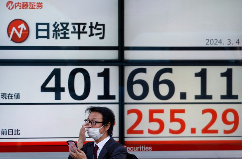 &copy; Reuters. A man uses a smartphone in front of an electronic screen displaying Japan's Nikkei share average outside a brokerage in Tokyo, Japan March 4, 2024. REUTERS/Kim Kyung-Hoon