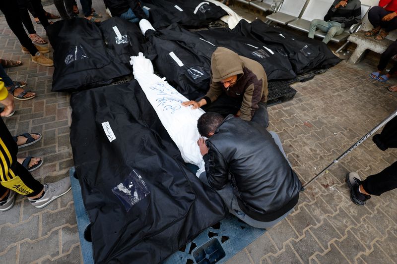 &copy; Reuters. أشخاص إلى جوار جثامين فلسطينيين قتلوا جراء غارة إسرائيلية على رفح جنوب قطاع غزة يوم الاثنين. تصوير: محمد سالم - رويترز