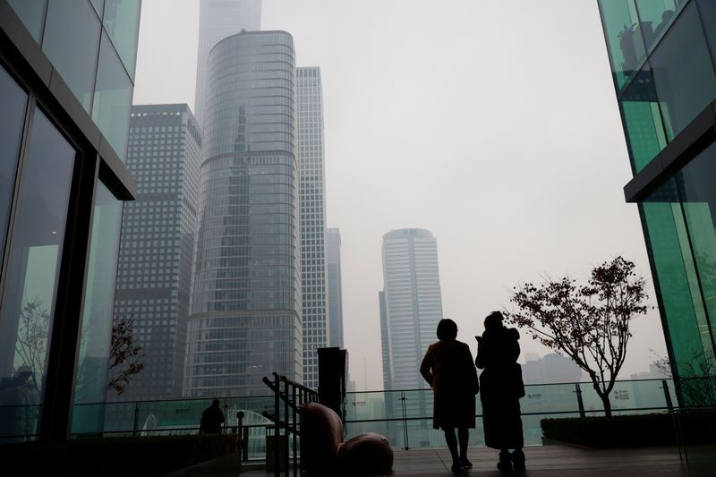 &copy; Reuters. People look at the skyline of the central business district (CBD), on the day of the opening session of the National People's Congress (NPC), during a hazy day in Beijing, China, March 5, 2021. REUTERS/Thomas Peter/ File Photo