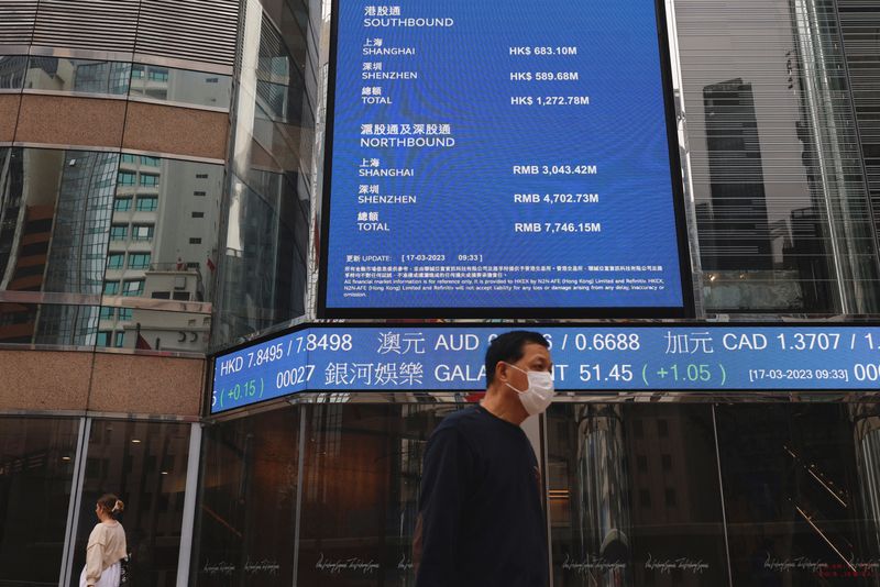 &copy; Reuters. FILE PHOTO: People walk past a screen displaying the Hang Seng Index at Central district, in Hong Kong, China March 17, 2023. REUTERS/Tyrone Siu/File Photo
