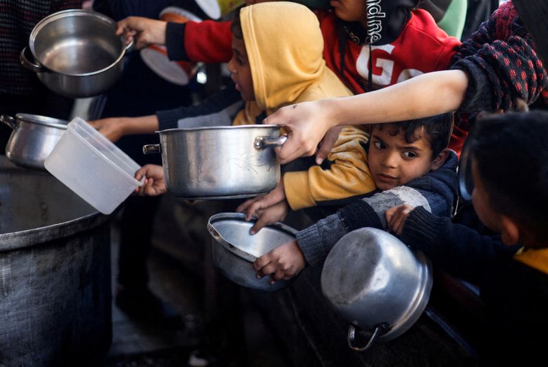 &copy; Reuters. Niños palestinos esperando para recibir alimentos cocinados por una cocina de caridad en medio de la escasez de suministros de alimentos, mientras continúa el conflicto entre Israel y el grupo islamista palestino Hamás, en Ráfah, sur de la Franja de G