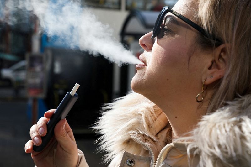 &copy; Reuters. A woman holds an e-cigarette as she vapes on a street in Manchester, Britain March 6, 2024. REUTERS/Temilade Adelaja