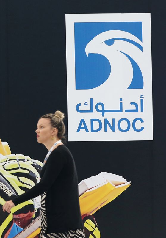 &copy; Reuters. زائرة تسير أمام شعار شركة أدنوك خلال مؤتمر للطاقة في أبوظبي بصورة من أرشيف رويترز.