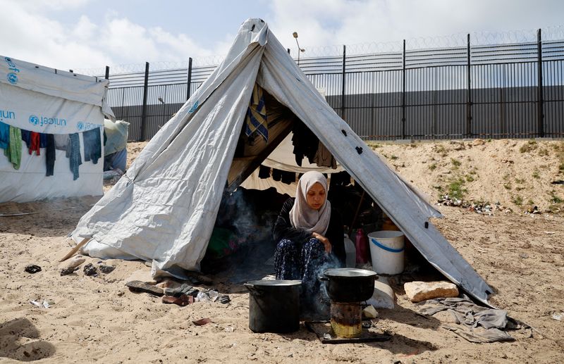 &copy; Reuters. سيدة فلسطينية نازحة، فرت من منزلها جراء الغارات الإسرائيلية، تجلس داخل معسكر خيام في رفح جنوبي غزة يوم الأربعاء . تصوير: محمد سالم - رويترز 