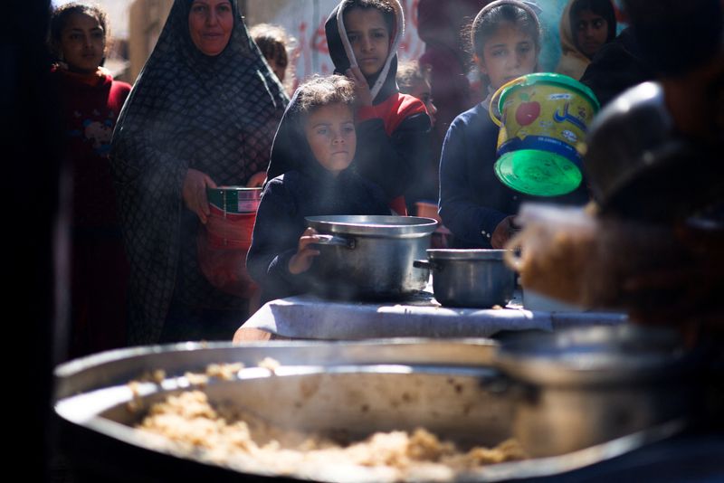 &copy; Reuters. أطفال فلسطينيون ينتظرون توزيع طعام يطهوه مطبخ تابع لإحدى الجمعيات الخيرية في رفح جنوبي قطاع غزة يوم الثلاثاء . تصوير: محمد سالم - رويترز