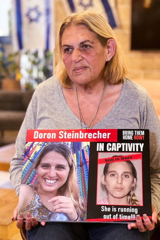 &copy; Reuters. سيمونا شتاينبرشر تحمل لافتة عليها صورتين لابنتها دورون الرهينة الإسرائيلية التي اختطفت في هجوم مقاتلي حركة حماس في السابع من أكتوبر تشرين 