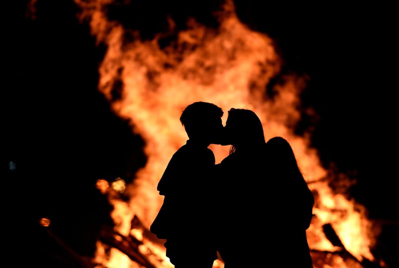 &copy; Reuters. FOTO DE ARCHIVO: Una pareja se besa junto a una hoguera en la playa de Poniente celebrando el solsticio de verano en Gijón, España. 24 de junio de 2017. REUTERS/Eloy Alonso/Archivo