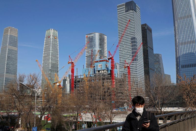 © Reuters. FILE PHOTO: A man walks past a construction site and skyscrapers at the central business district (CBD) during morning rush hour, ahead of the opening of the National People's Congress (NPC), in Beijing, China, February 29, 2024. REUTERS/Florence Lo/File Photo