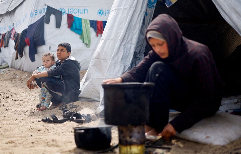 &copy; Reuters. Bambini palestinesi sfollati, fuggiti dalle loro case a causa degli attacchi israeliani, siedono in una tendopoli, nel contesto del conflitto in corso tra Israele e il gruppo islamista palestinese Hamas, a Rafah, nel sud della Striscia di Gaza, 6 marzo 20