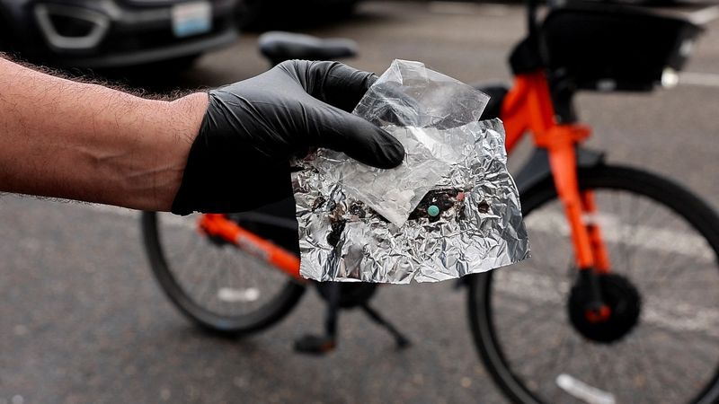 &copy; Reuters. FILE PHOTO: Portland police officer David Baer holds up a blue oxycodone pill and a small bag of fentanyl that he just confiscated from a woman getting ready to smoke them in her car in downtown Portland, Oregon, U.S. February 7, 2024. These blue pills ar