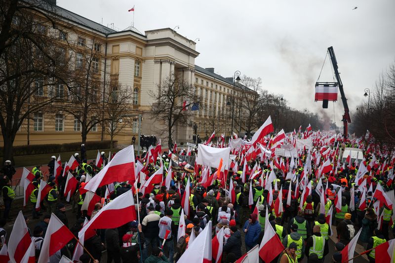 &copy; Reuters. FOTO DE ARCHIVO: Personas llevan banderas polacas y pancartas, mientras los agricultores protestan frente a la oficina del primer ministro polaco, Donald Tusk, contra el Acuerdo Verde de la Unión Europea y las importaciones de productos agrícolas ucrani