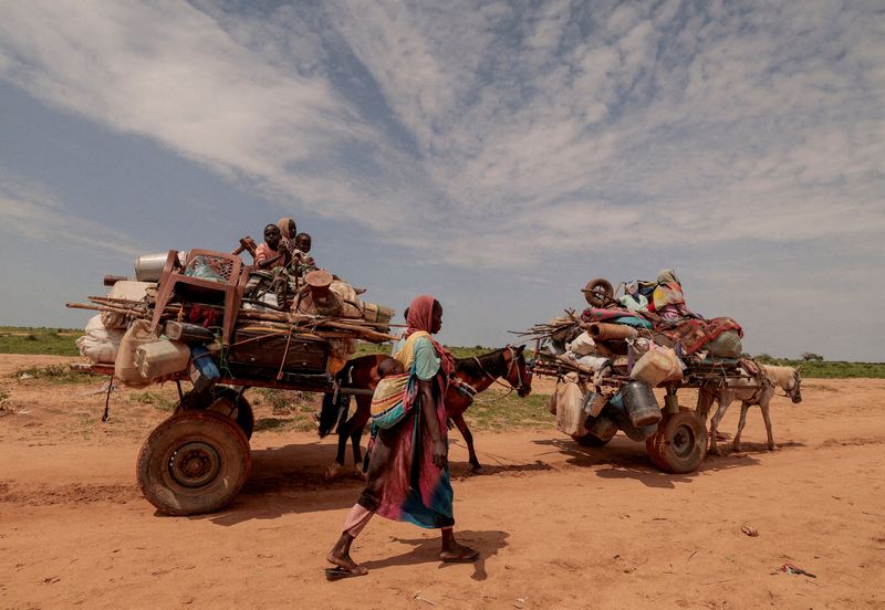 &copy; Reuters. FILE PHOTO: A Sudanese woman, who fled the conflict in Murnei in Sudan's Darfur region, walks beside carts carrying her family belongings upon crossing the border between Sudan and Chad in Adre, Chad August 2, 2023. REUTERS/Zohra Bensemra/File Photo