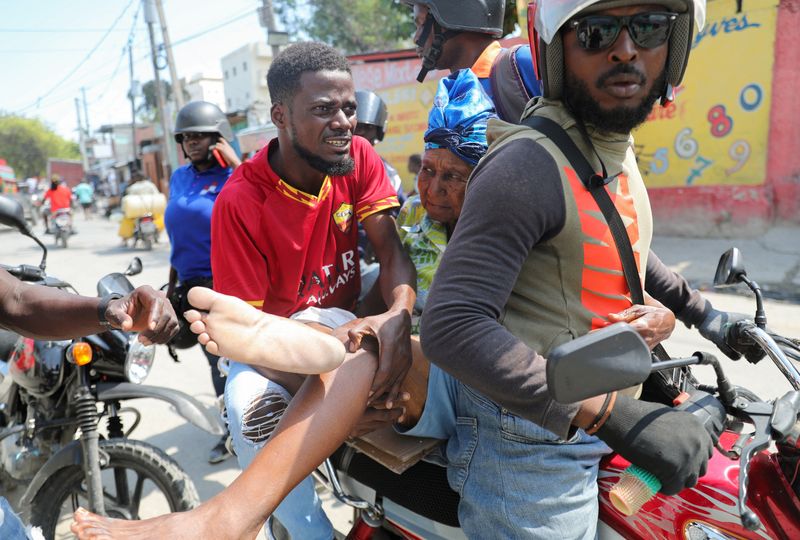 © Reuters. A woman with a gunshot wound is transported by two men on a motorcycle as Haiti remains in state of emergency due to the violence, in Port-au-Prince, Haiti March 9, 2024. REUTERS/Ralph Tedy Erol