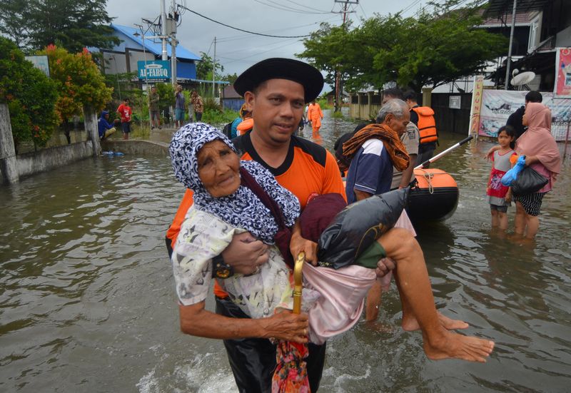 &copy; Reuters. أحد أفراد وكالة الكوارث الإندونيسية يقوم بإجلاء امرأة مسنة من منطقة سكنية تضررت جراء فيضانات في بادانج بإقليم سومطرة الغربية في إندونيسيا 