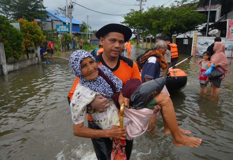 &copy; Reuters. Un agente de la Agencia Local de Gestión de Desastres (BPBD) evacua a una anciana de una zona residencial afectada por las inundaciones debidas a las fuertes lluvias, en Padang, provincia de Sumatra Occidental, Indonesia. 8 de marzo de 2024, en esta foto
