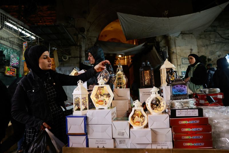 &copy; Reuters. امرأة تمسك فانوسا في سوق مع حلول شهر رمضان في المدينة القديمة بالقدس يوم الأحد. تصوير: عمار عوض - رويترز