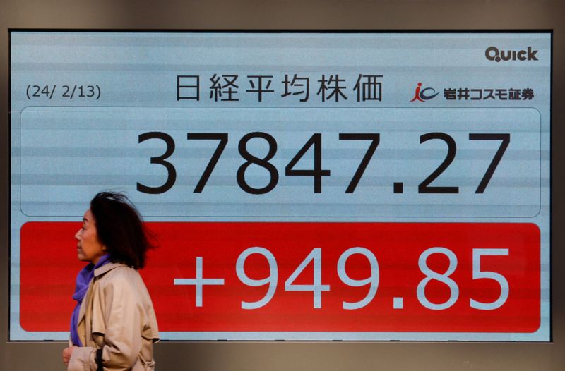 &copy; Reuters. A passerby walks past in front of an electric screen displaying Japan's Nikkei share average outside a brokerage in Tokyo, Japan February 13, 2024.  REUTERS/Issei Kato