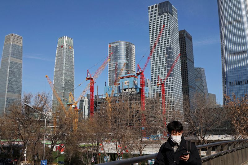 &copy; Reuters. FILE PHOTO: A man walks past a construction site and skyscrapers at the central business district (CBD) during morning rush hour, ahead of the opening of the National People's Congress (NPC), in Beijing, China, February 29, 2024. REUTERS/Florence Lo/File 