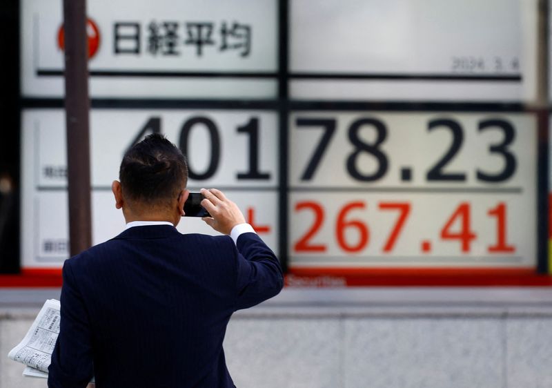 &copy; Reuters. رجل يلتقط صورة للوحة إلكترونية تعرض حركة تداول الأسهم على المؤشر نيكي الياباني خارج مكتب للسمسرة بطوكيو في الرابع من مارس آذار 2024 . تصوير: كي