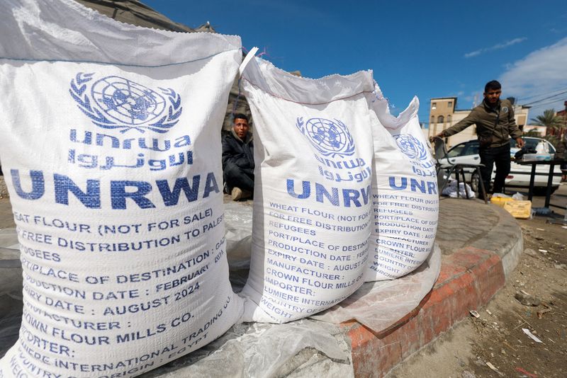 © Reuters. FILE PHOTO: Displaced Palestinians wait to receive United Nations Relief and Works Agency (UNRWA) aid, amid the ongoing conflict between Israel and the Palestinian Islamist group Hamas, in Rafah, in the southern Gaza Strip, March 7, 2024. REUTERS/Mohammed Salem/File Photo