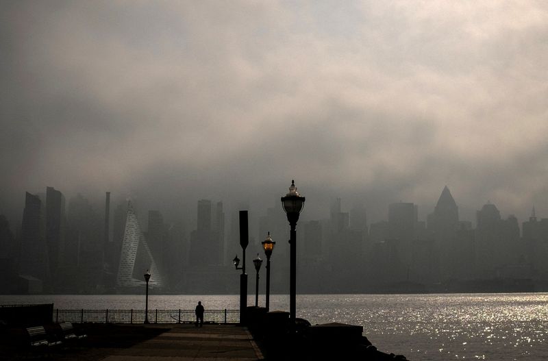 &copy; Reuters. FILE PHOTO: A person stands on the Hudson River shoreline as heavy fog hangs over the skyline of New York City and midtown Manhattan in the background, in Weehawken, New Jersey, U.S., February 27, 2024. REUTERS/Mike Segar/File Photo