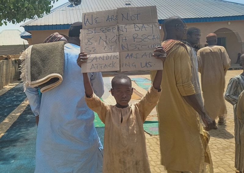 &copy; Reuters. طفل يرفع لوحة للاحتجاج على ما وصفه مدرس وأولياء أمور ومسؤول محلي بقيام مسلحين باختطاف المئات من الطلاب في مدرسة بولاية كادونا شمال غرب نيجي