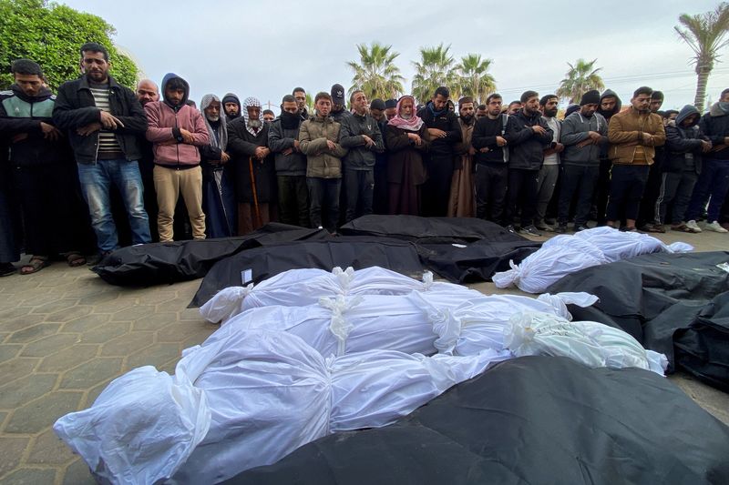 © Reuters. مشيعون يصلون بجوار جثامين فلسطينيين قتلوا جراء الهجمات الإسرائيلية في مستشفي الأقصي بدير البلح في وسط قطاع غزة يوم 23 فبراير شباط 2024. تصوير: دعاء روقة - رويترز