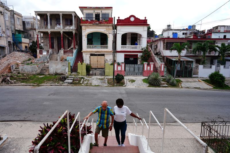 &copy; Reuters. Jorge Enrique is helped by caregiver Silvia Garcia to walk back home after exercising at a nearby park in Havana, Cuba, March 8, 2024. REUTERS/Alexandre Meneghini