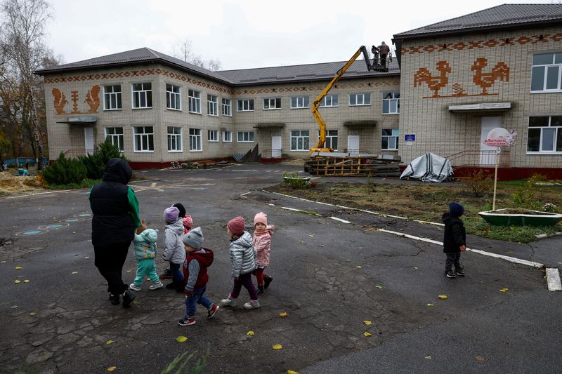 &copy; Reuters. A teacher with children walks in front of a building of a kindergarten, which was damaged on the first months of Russia's attack on Ukraine in the town of Okhtyrka, Sumy region, Ukraine November 2, 2023. REUTERS/Valentyn Ogirenko
