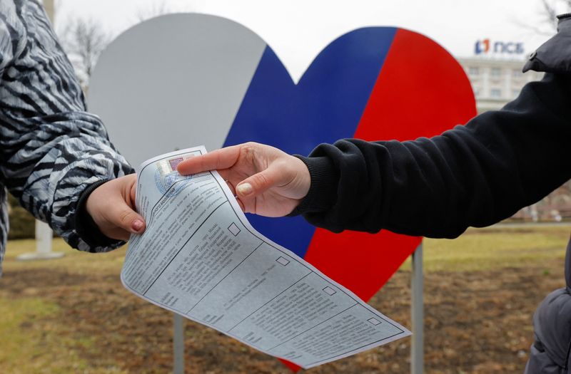 &copy; Reuters. عضو بلجنة انتخابية متنقلة يسلم بطاقة اقتراع لناخب خلال التصويت المبكر بالانتخابات الرئاسية الروسية في منطقة دونيتسك الأوكرانية التي تسيطر