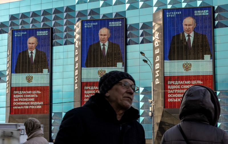 &copy; Reuters. أشخاص ينتظرون حافلة بجوار شاشات إلكترونية على واجهة مبنى تعرض صورة الرئيس الروسي فلاديمير بوتين في موسكو يوم 29 فبراير شباط 2024. تصوير: مكسيم 