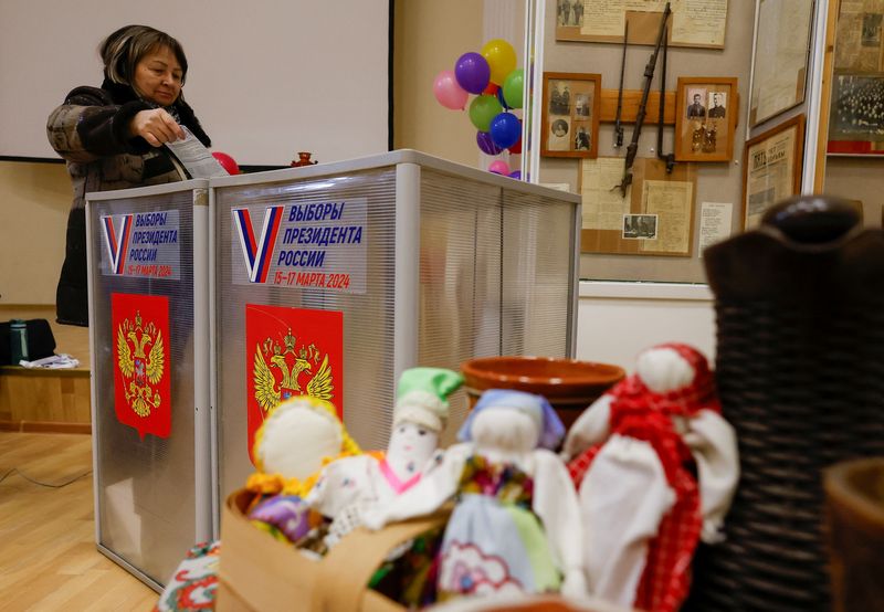 &copy; Reuters. Una donna vota accanto alle decorazioni per la celebrazione della "Maslenitsa", o "Settimana grassa ", una festività pagana che segna la fine dell'inverno, in un seggio elettorale durante le elezioni presidenziali a Vidnoye, nella regione di Mosca, in Ru