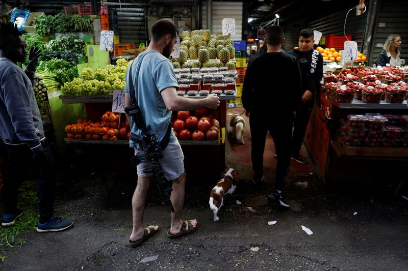 &copy; Reuters. رجل يحمل بندقية يمشي في سوق بتل أبيب في إسرائيل في الثامن من فبراير شباط 2024. تصوير: سوزانا بيرا - رويترز
