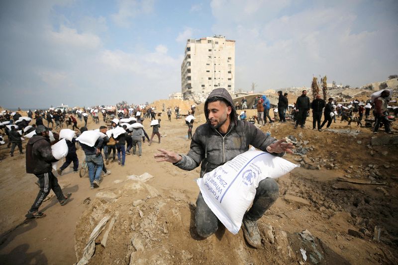 &copy; Reuters. فلسطينيون يحملون أكياسا من الدقيق في مدينة غزة يوم 19 فبراير شباط 2024. تصوير: قصي النمر - رويترز