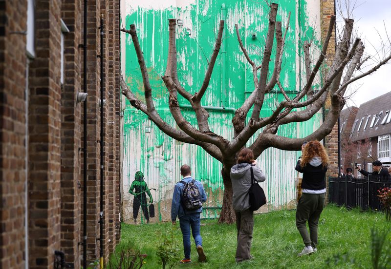 &copy; Reuters. Un grupo de personas observa un nuevo mural atribuido al artista británico Banksy en una pared del norte de Londres, Reino Unido. 18 de marzo de 2024. REUTERS/Toby Melville