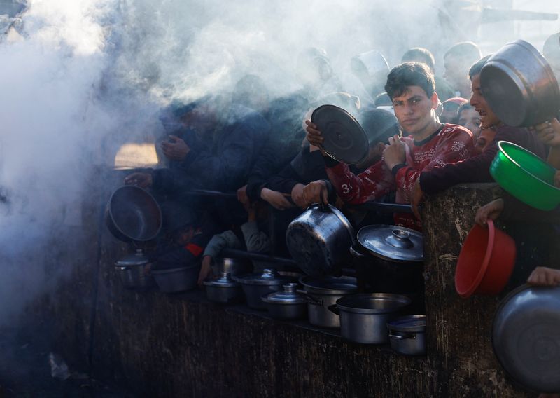 © Reuters. فلسطينيون في انتظار الحصول على طعام خلال شهر رمضان في رفح جنوب قطاع غزة يوم 13 مارس آذار 2024. تصوير: محمد سالم - رويترز