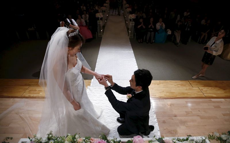 © Reuters. FILE PHOTO: A groom puts a wedding ring on his bride's finger during a wedding ceremony at a budget wedding hall at the National Library of Korea in Seoul, South Korea, May 16, 2015. REUTERS/Kim Hong-Ji