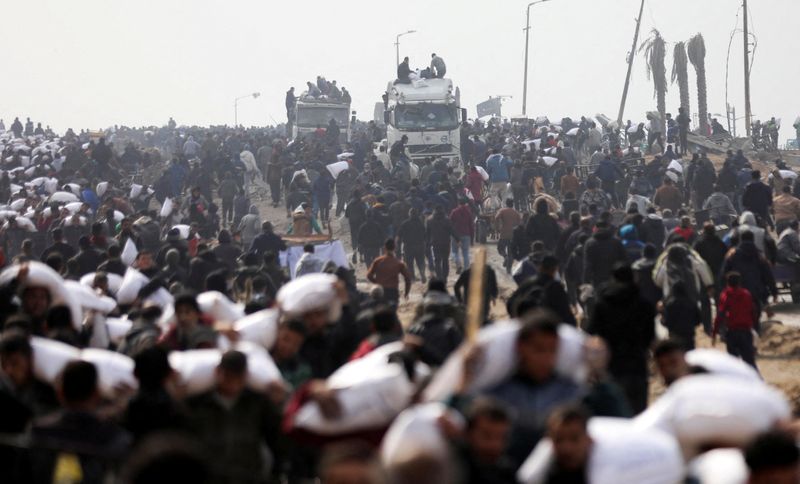 &copy; Reuters. فلسطينيون يحملون أكياسا من الطحين بعد الحصول عليها من شواحن مساعجات بالقرب من نقطة تفتيش إسرائيلية في غزة يوم الثلاثاء. تصوير: قصي النمر - رو