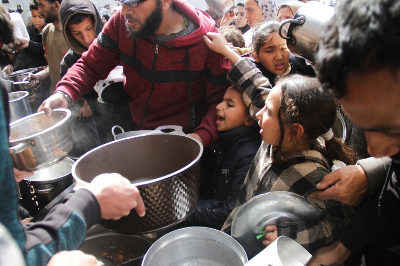 © Reuters. فلسطينيون يحاولون الحصول على طعام مجاني في مخيم جباليا للاجئين في شمال غزة يوم الثلاثاء. تصوير: محمود عيسى - رويترز

