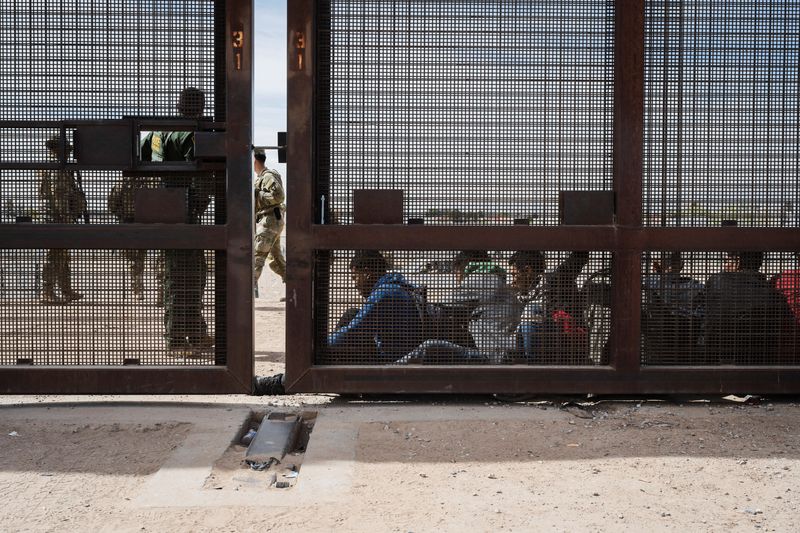 © Reuters. A group of migrants sit as they wait to be transported for processing on the day the U.S. 5th Circuit Court of Appeals hears oral arguments on Texas' motion to lift a block on its SB4 immigration law that would allow state officials to arrest migrants suspected of being in the country illegally, in El Paso, Texas, U.S. March 20, 2024