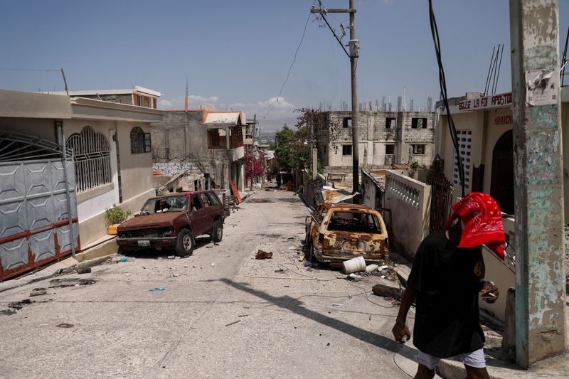 &copy; Reuters. A person walks past damaged cars in the Carrefour Feuilles neighborhood, which was deserted due to gang violence, in Port-au-Prince, Haiti March 19, 2024. REUTERS/Ralph Tedy Erol