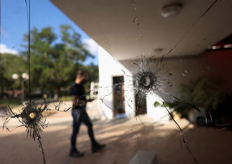 &copy; Reuters. FOTO DE ARCHIVO: Un hombre camina detrás de un cristal con agujeros de bala tras el mortal ataque del 7 de octubre perpetrado por hombres armados del grupo militante palestino Hamás desde la Franja de Gaza, en el kibutz Nir Oz, en el sur de Israel. 21 d