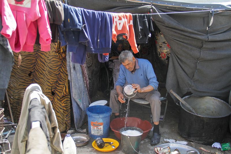 &copy; Reuters. نازح فلسطيني يغسل أدوات المطبخ في مدرسة تابعة للأونروا تؤوي النازحين خلال شهر رمضان في مخيم جباليا بشمال قطاع غزة يوم الأربعاء. تصوير: محمود