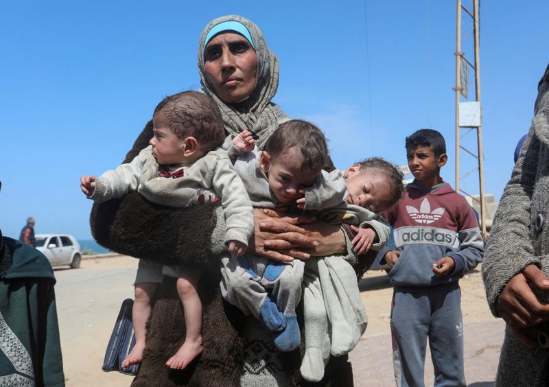 &copy; Reuters. Una mujer palestina que huye del hospital Al Shifa tras una incursión israelí, lleva a sus hijos trillizos mientras avanza hacia el sur, en medio del actual conflicto entre Israel y Hamás, en el centro de la Franja de Gaza. 21 de marzo de 2024. REUTERS