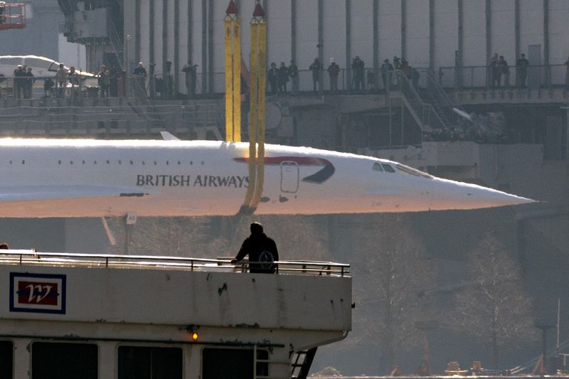 &copy; Reuters. British Airways Concorde supersonic jet is lifted from a barge on the Hudson River to its resting place at the Intrepid Museum, as a man looks on from the deck of a passing New York Waterway ferry boat in New York City, U.S., March 14, 2024. REUTERS/Mike 